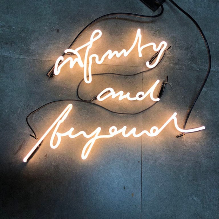 Warm white LED neon sign reading infinity and beyond on a concrete wall