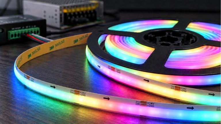 Addressable COB LED tape with a luminous front and yellow adhesive backing on a black reel.