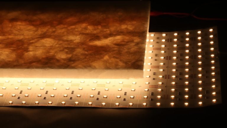 Warm-white flexible LED light sheet illuminating a translucent stone panel from behind.