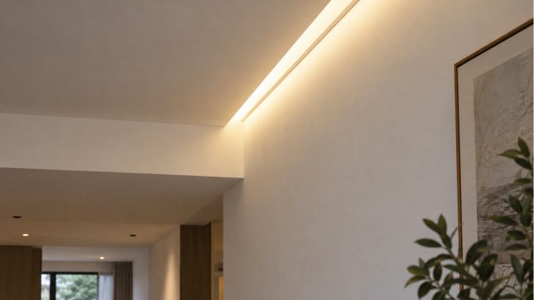 Concealed linear LED lighting washing a textured wall beside a ceiling recess.