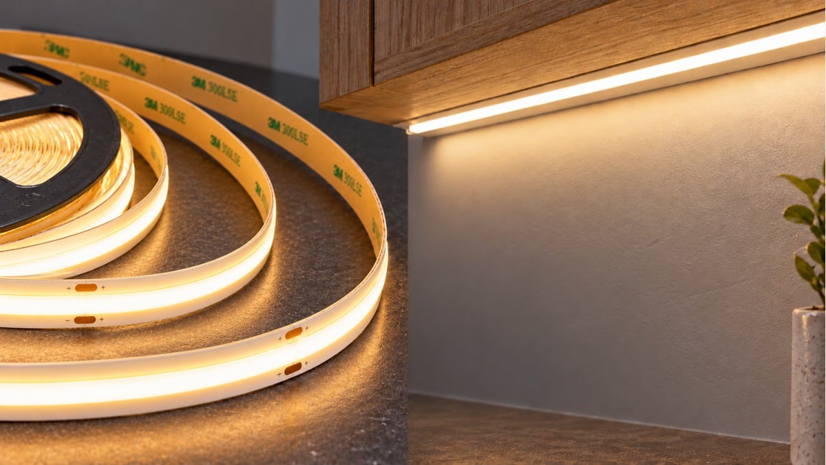 Warm-white COB LED tape with yellow adhesive backing beside an under-cabinet lighting example.