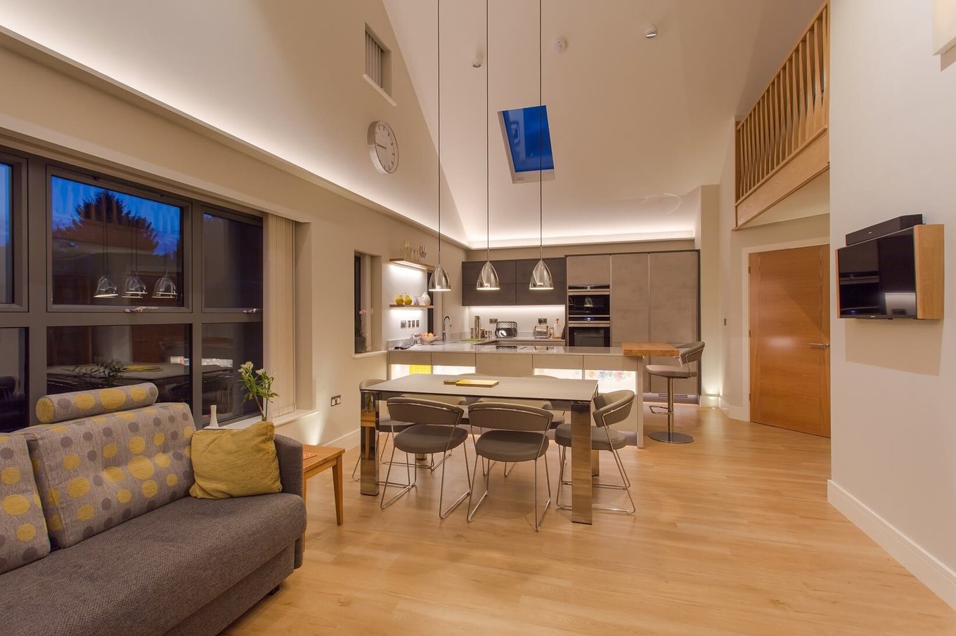 Open-plan living and dining room lit with concealed LED strip along the ceiling