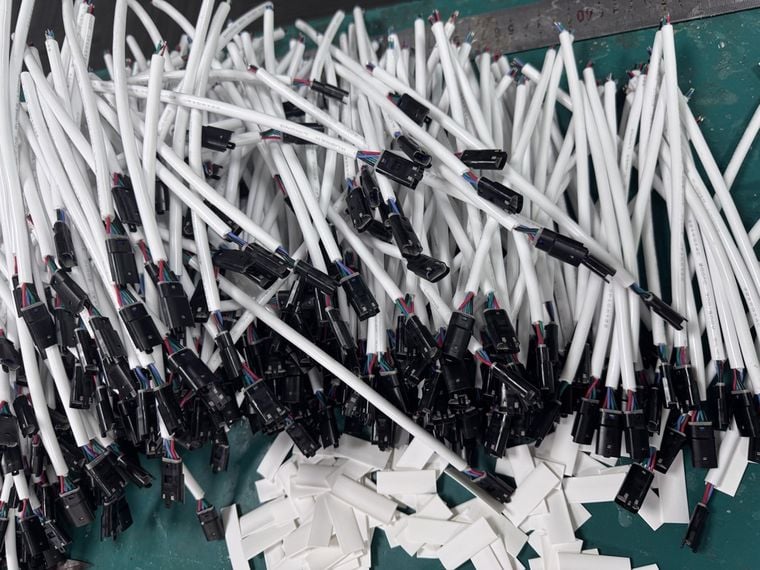 Heat-shrink sleeves slid over LED strip connector lead joints before shrinking
